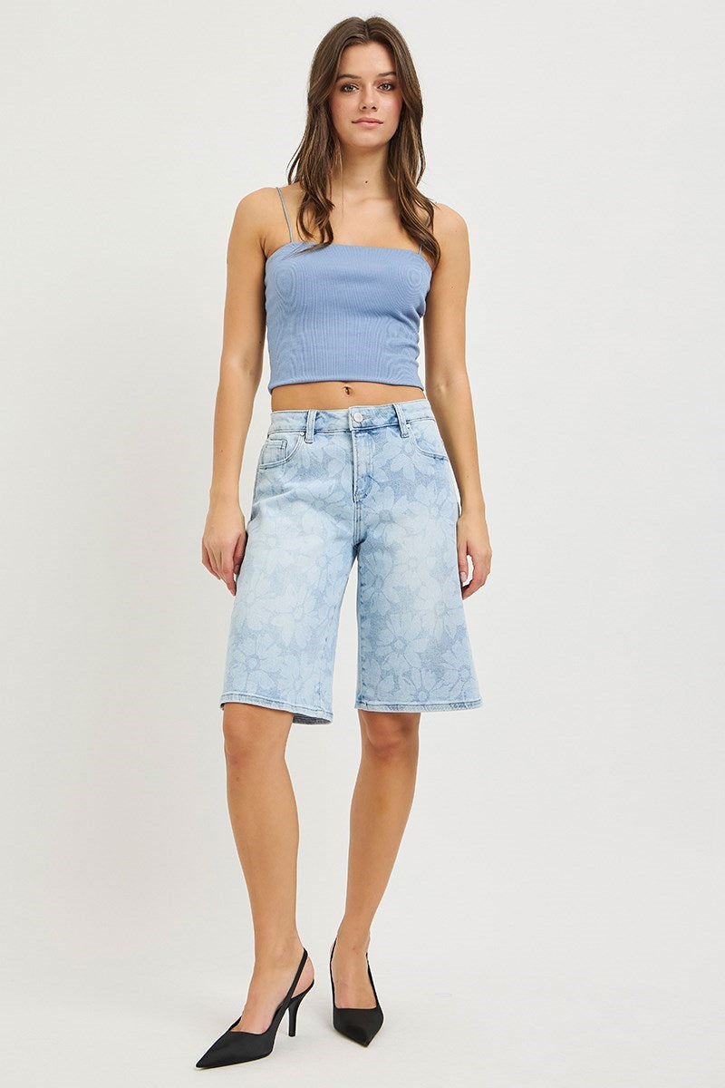 Woman wearing denim bermuda shorts and blue tank on plain background