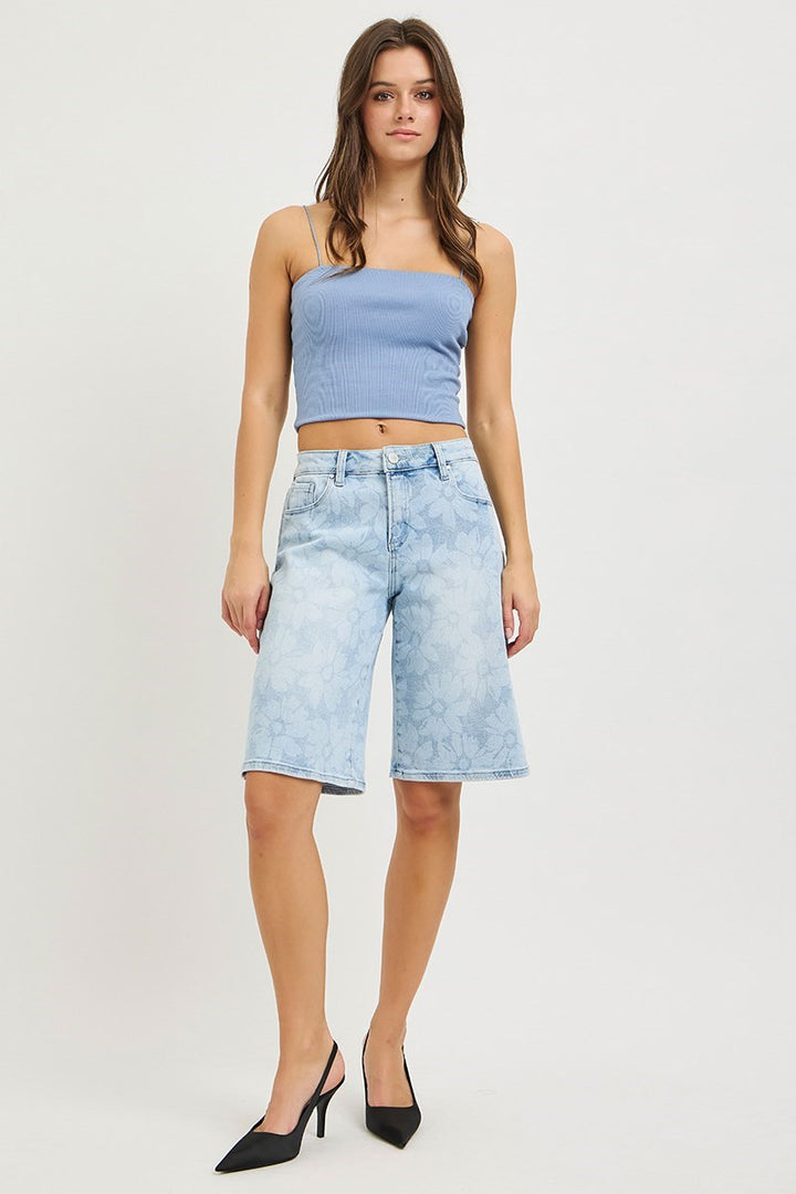 Woman wearing denim bermuda shorts and blue tank on plain background