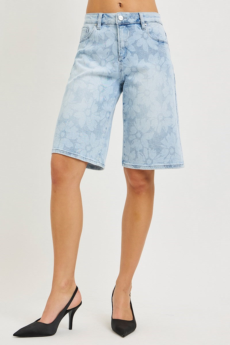 woman wearing denim bermuda shorts with floral pattern on plain background