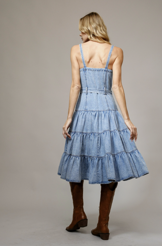 Woman wearing a denim dress with brown boots on a plain background