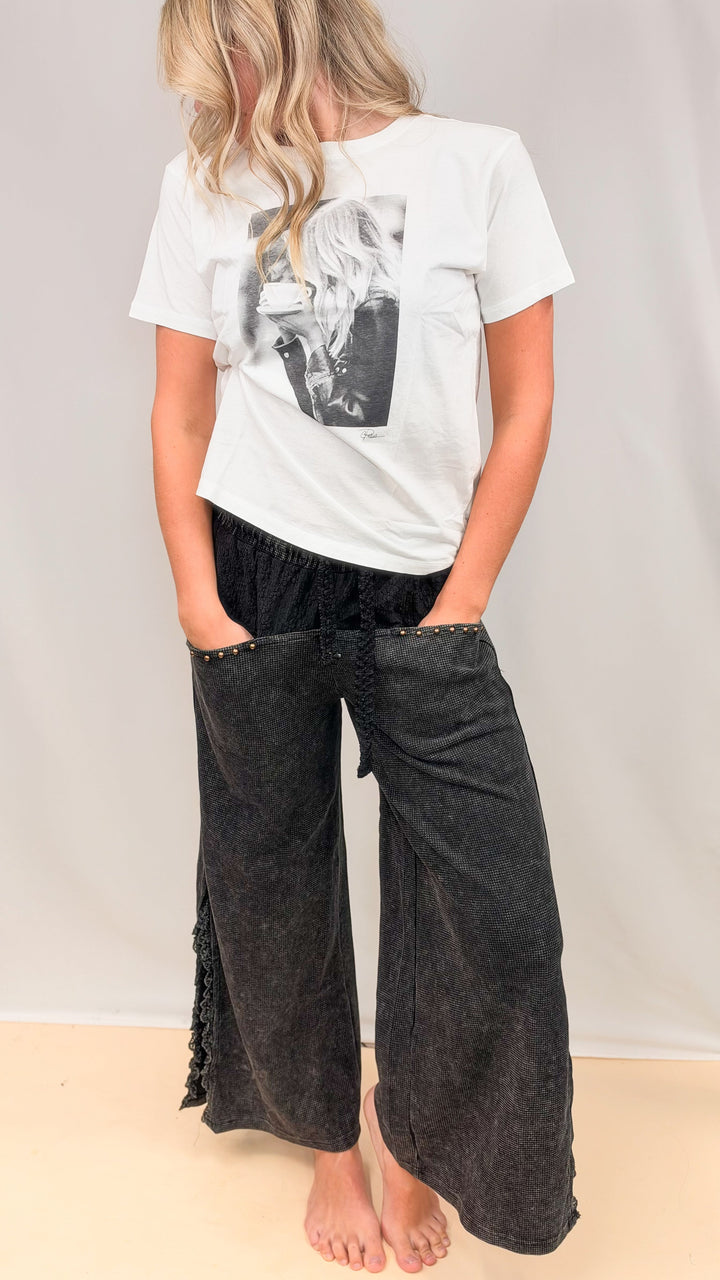 Woman wearing black pants and graphic tee on plain background
