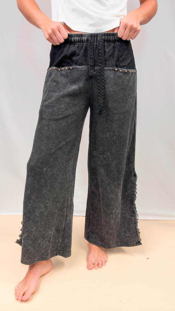 Woman wearing black waffle knit pants with lace details on plain background