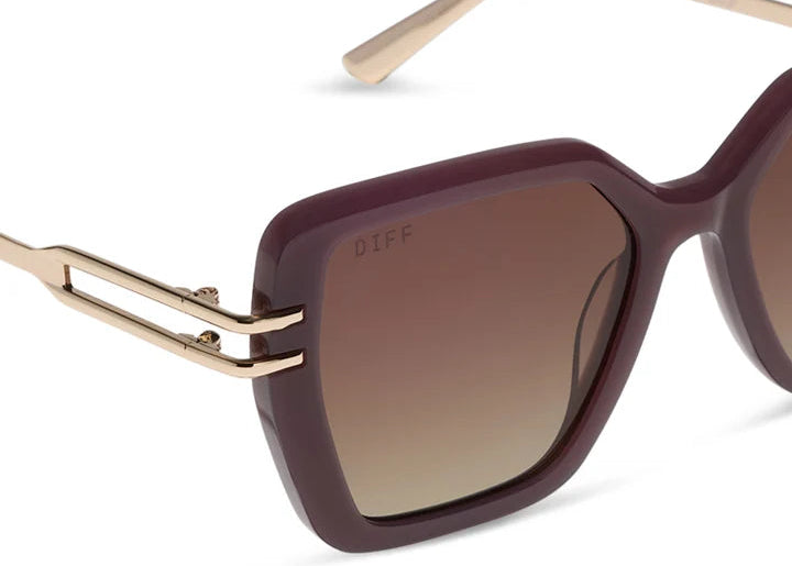 Close up of brown and gold sunglasses with brown gradient lenses on white background