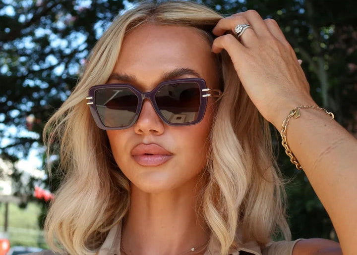 Woman wearing brown and gold sunglasses standing outdoors