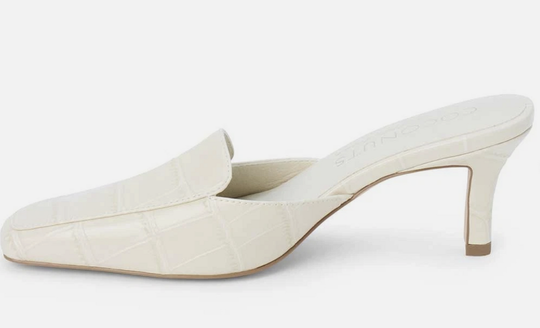A single cream-colored mule heel with a crocodile-embossed texture, shown from a side profile against a light gray background.