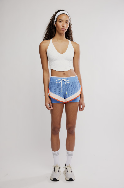 Woman wearing a white tank top and blue shorts with a colorful stripe on a white background