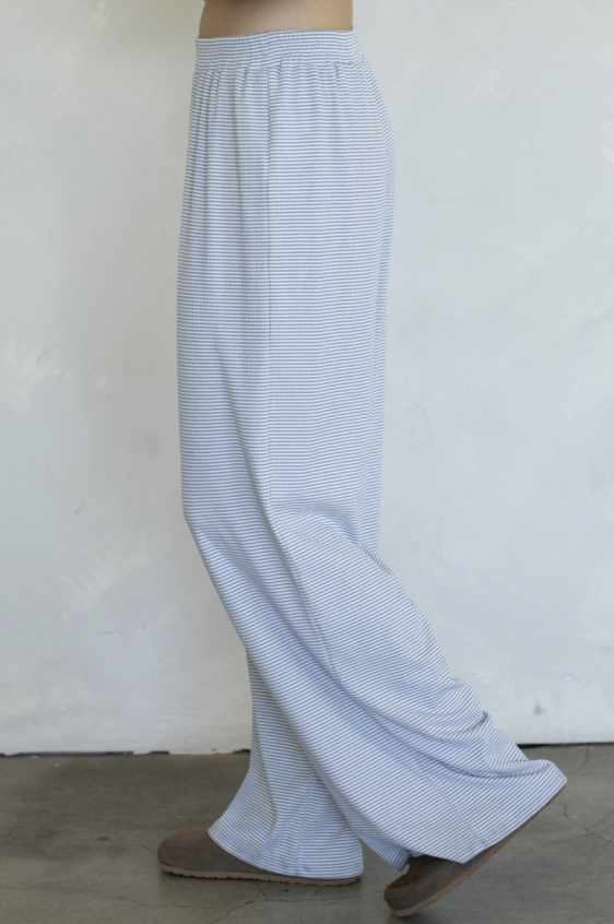 Woman wearing blue stripe pants on plain background