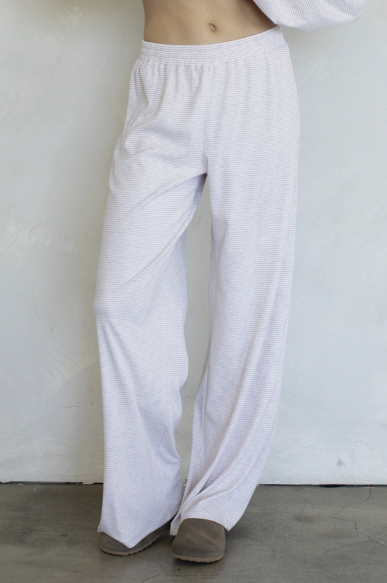 Woman wearing purple stripe pants on plain background