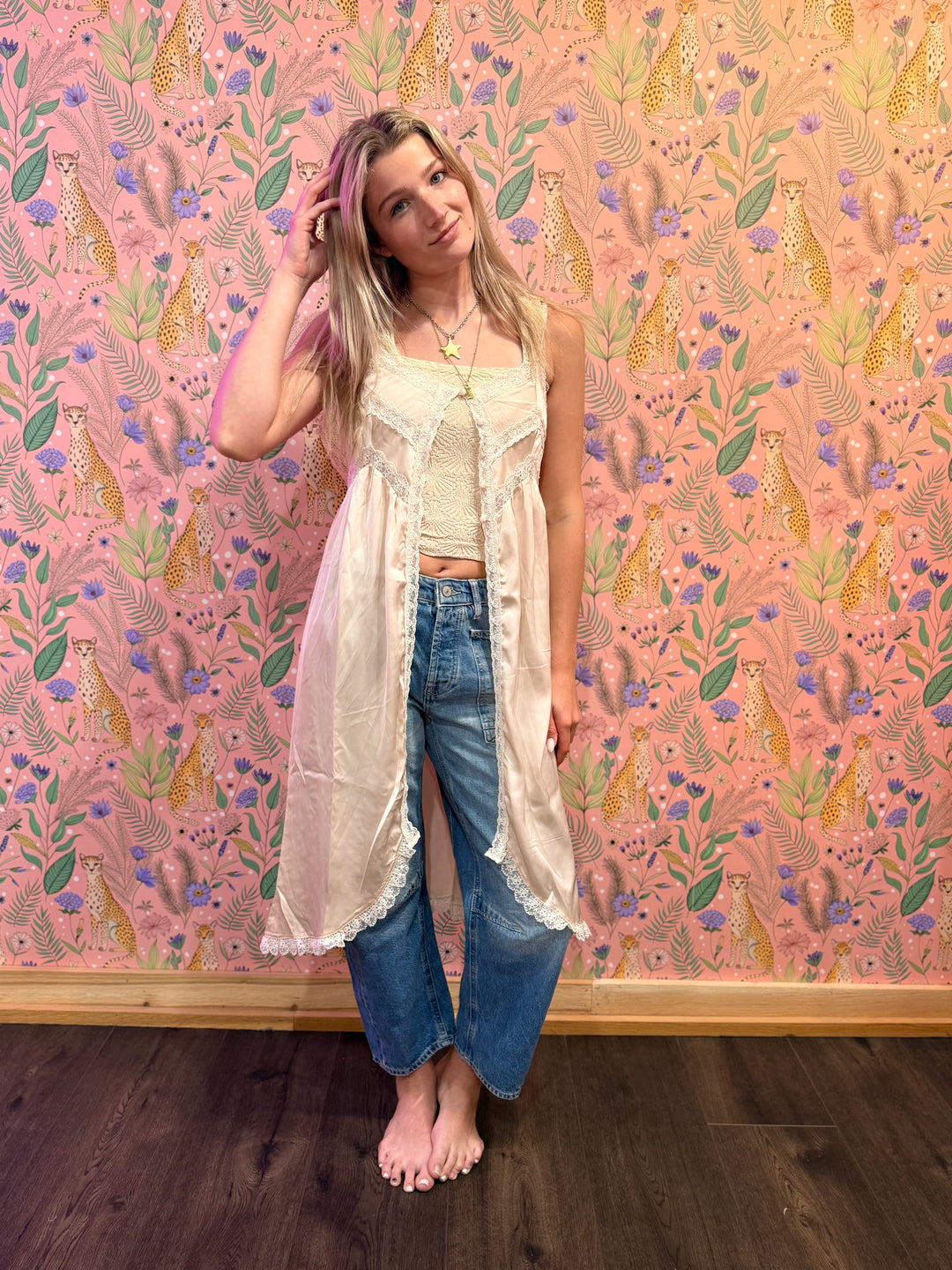 Woman standing in front of a pink wall with a floral and animal pattern