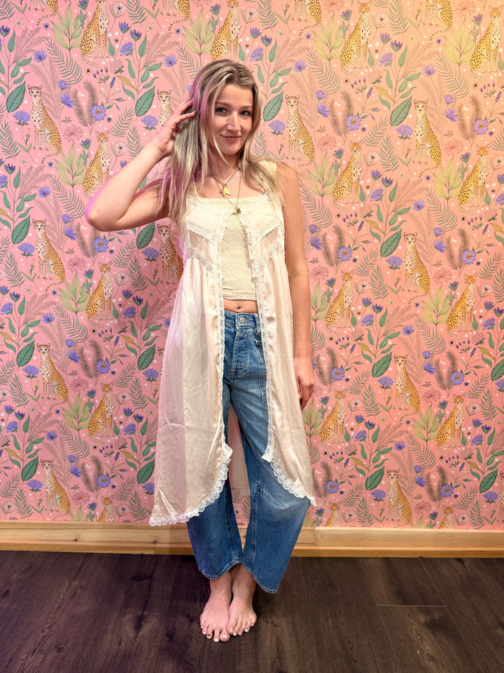Woman standing in front of a pink wall with a floral and animal pattern