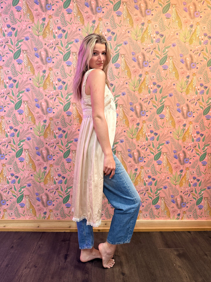 Woman standing against a pink wall with a colorful animal and floral pattern