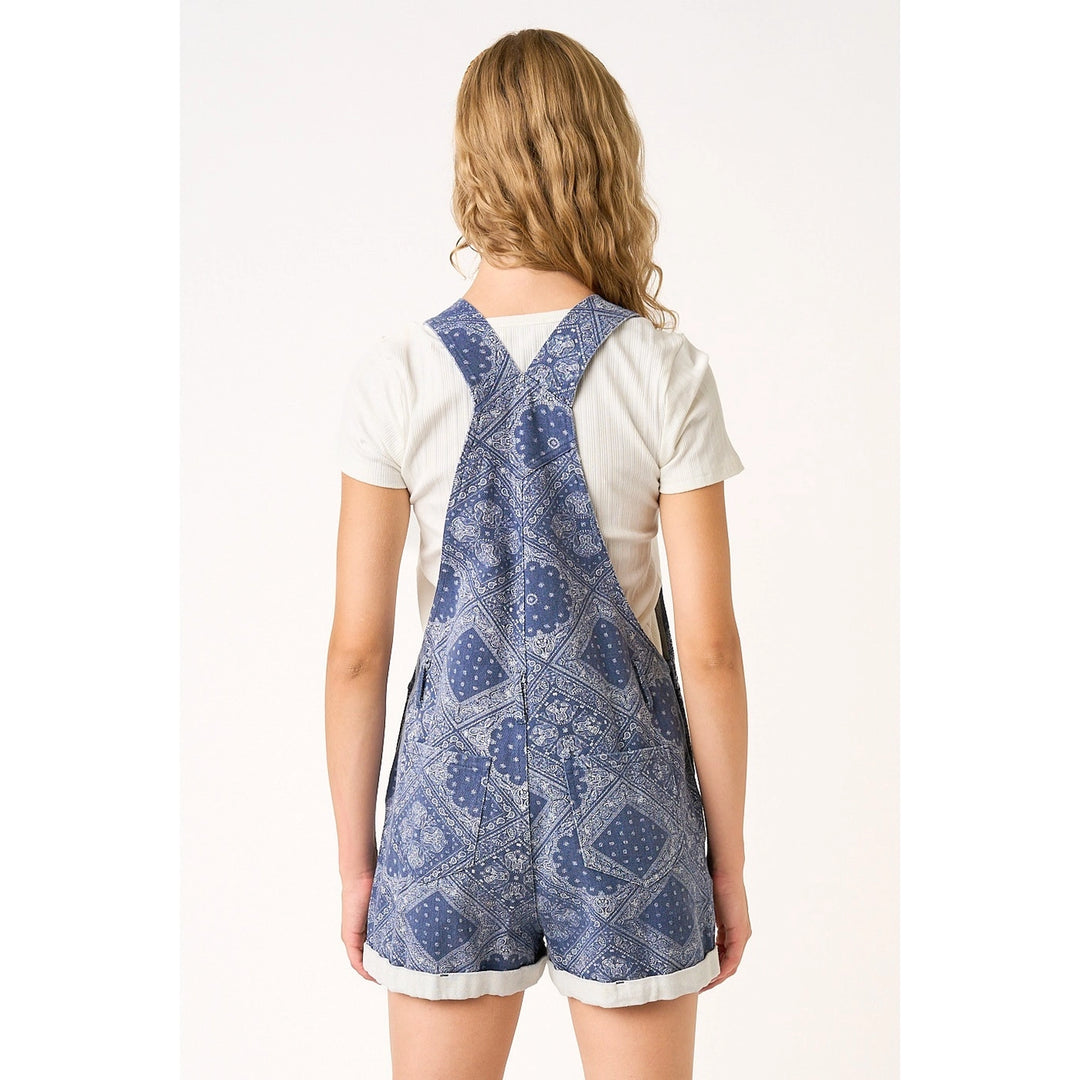 Person wearing a blue patterned romper with a white shirt underneath on a white background