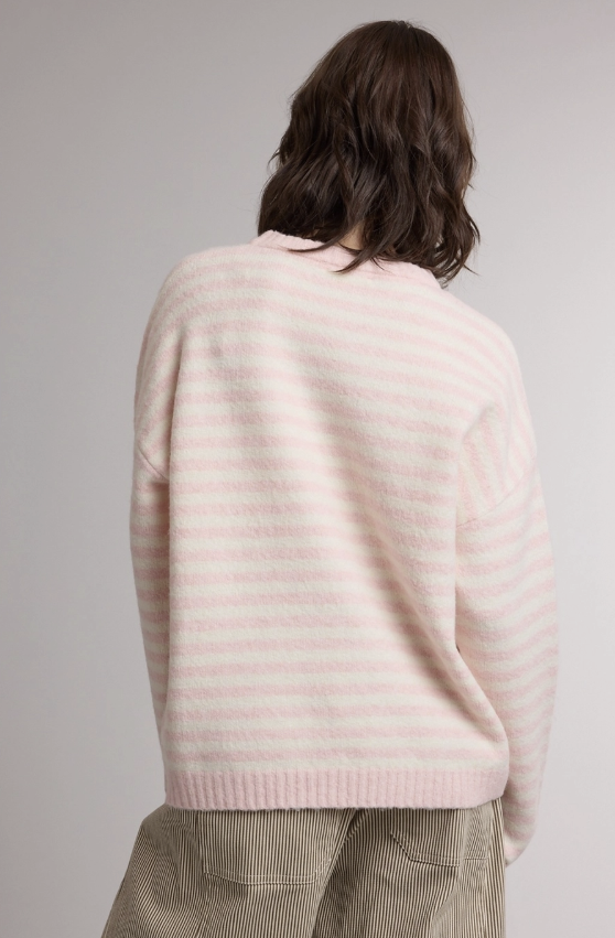A person shown from the back wearing a light pink and white striped knit sweater and beige corduroy pants against a plain light gray studio background.
