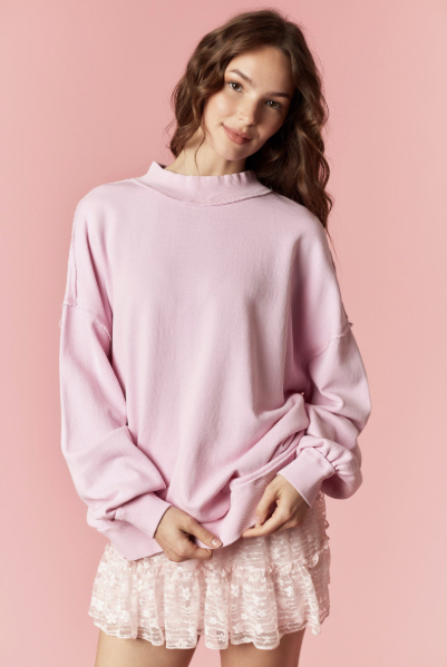 Woman wearing a pink sweater and lace skirt against a pink background