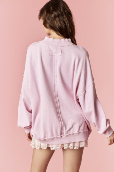 Person wearing a pink oversized jacket with lace trim on a pink background