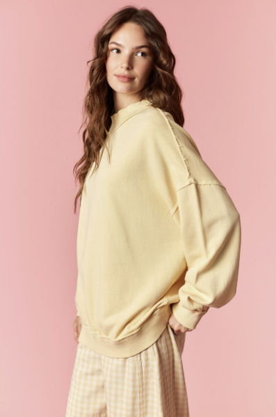 Woman wearing a light yellow oversized sweater against a pink background