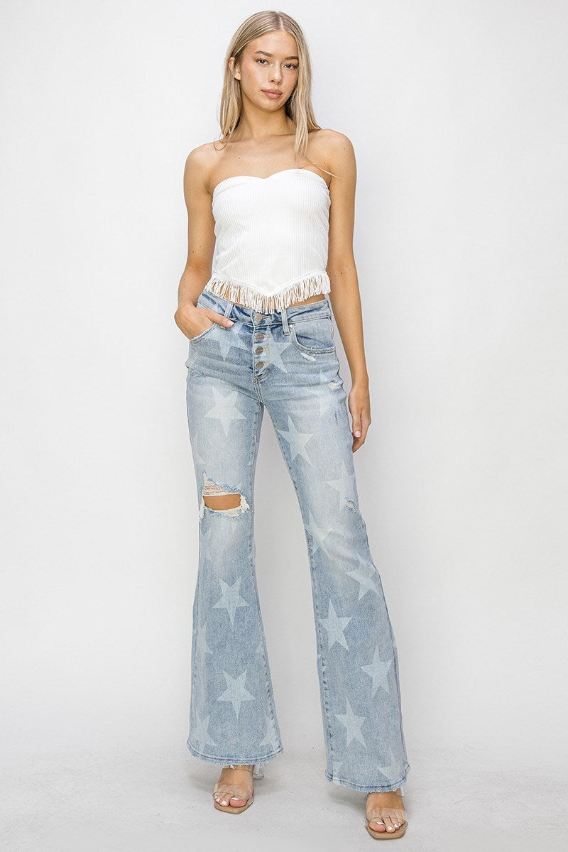 Woman wearing a white strapless top and light blue jeans with star patterns on a white background