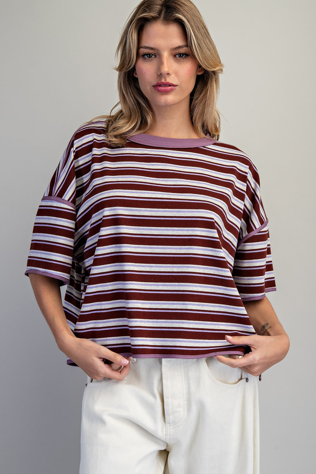 Woman wearing purple stripe tee on plain background