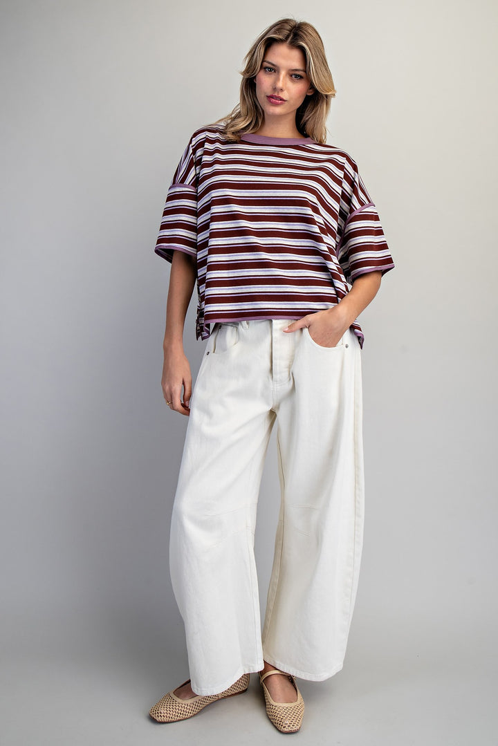 Woman wearing a striped shirt and white pants against a plain background