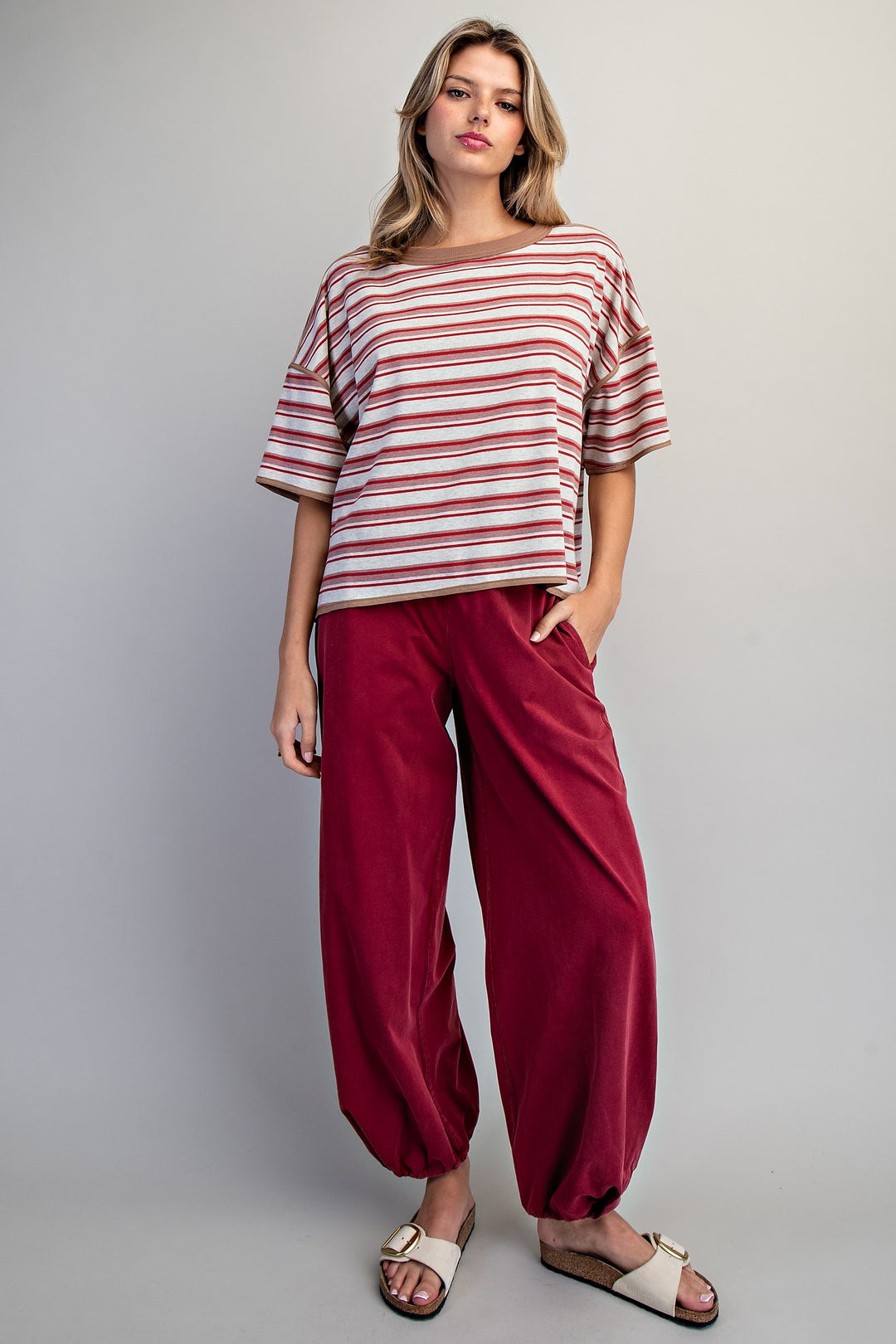 Woman wearing red stripe tee and red pants on plain background