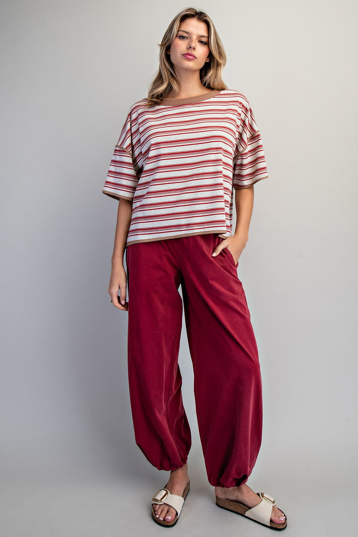 Woman wearing red stripe tee and red pants on plain background