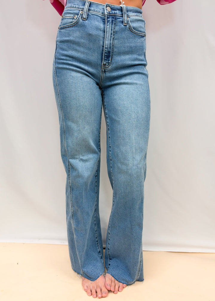 Woman wearing medium wash wide leg  denim jeans on plain background