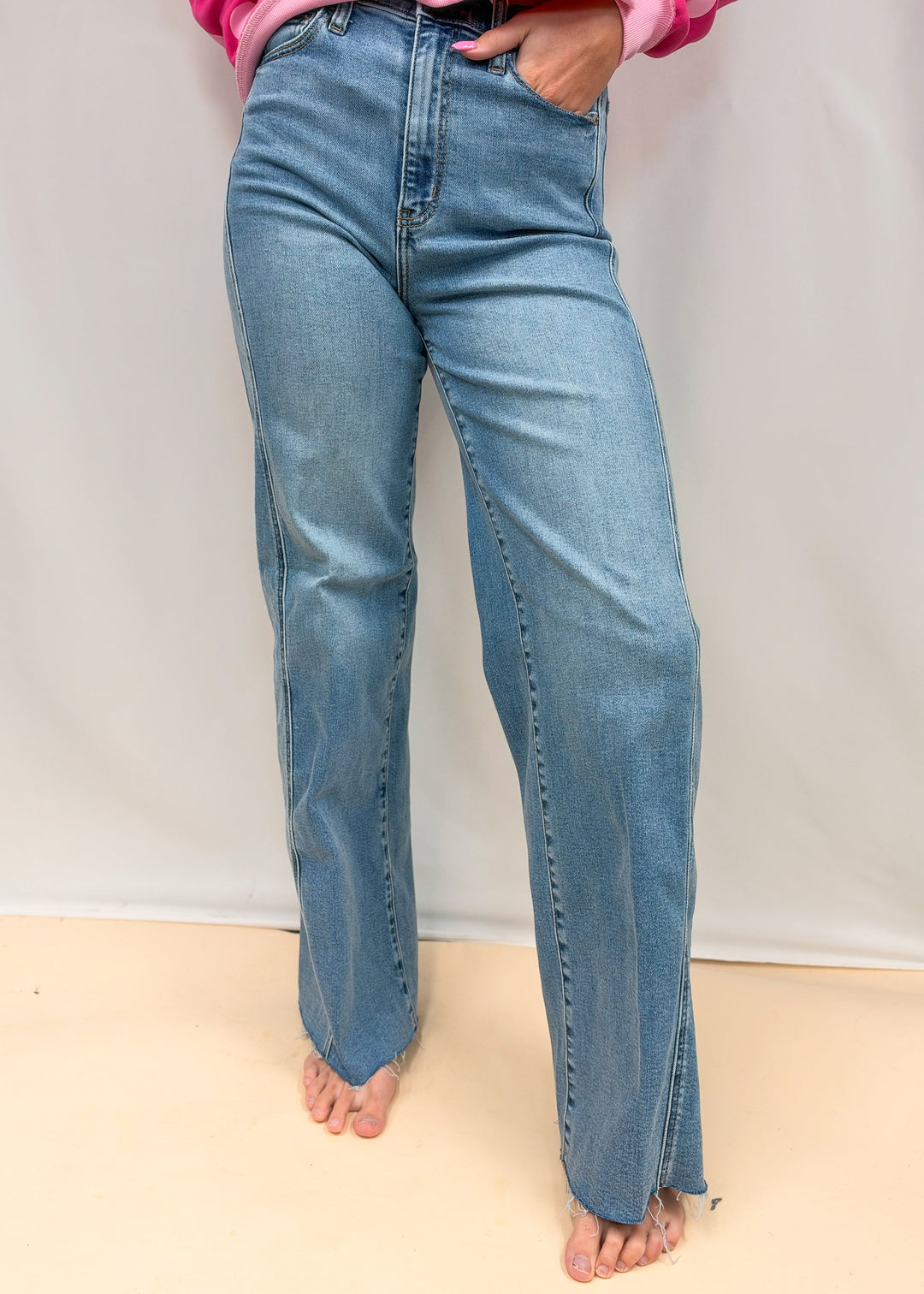 Woman wearing medium wash wide leg denim jeans on plain background