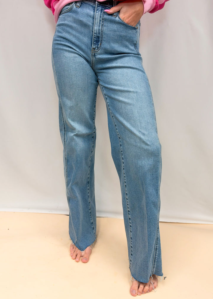 Woman wearing medium wash wide leg denim jeans on plain background