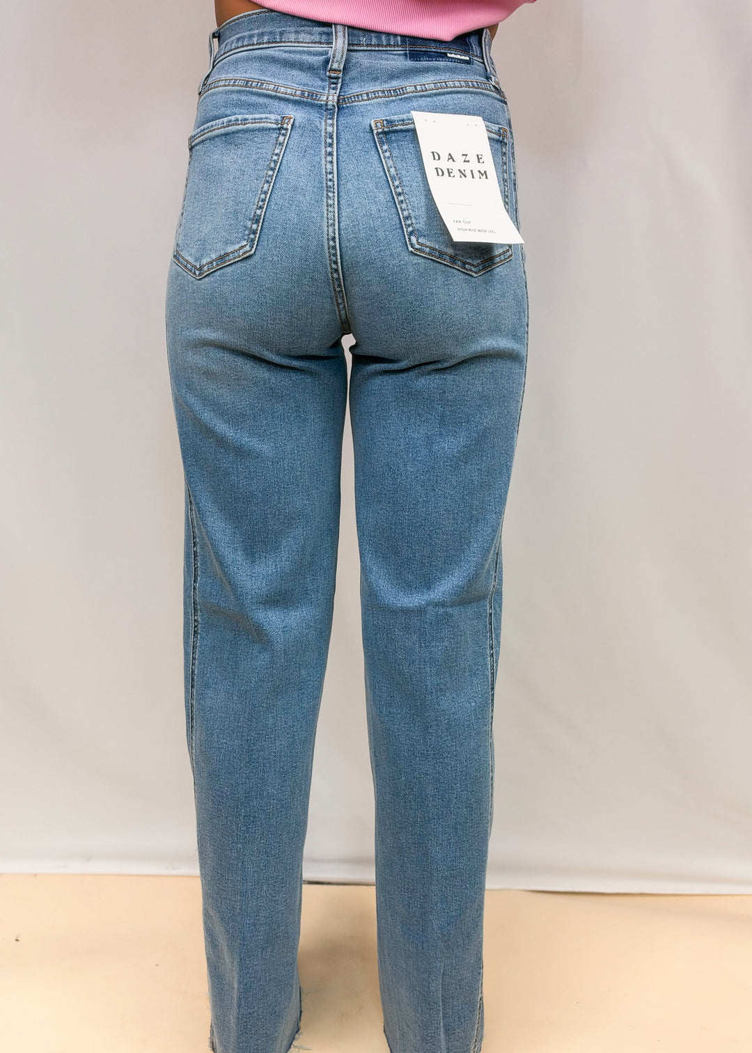 Woman shown from back wearing medium wash wide leg denim jeans on plain background