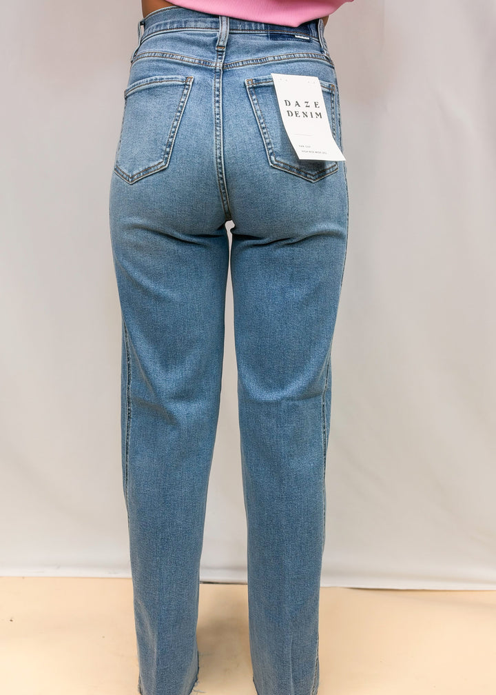 Woman shown from back wearing medium wash wide leg denim jeans on plain background