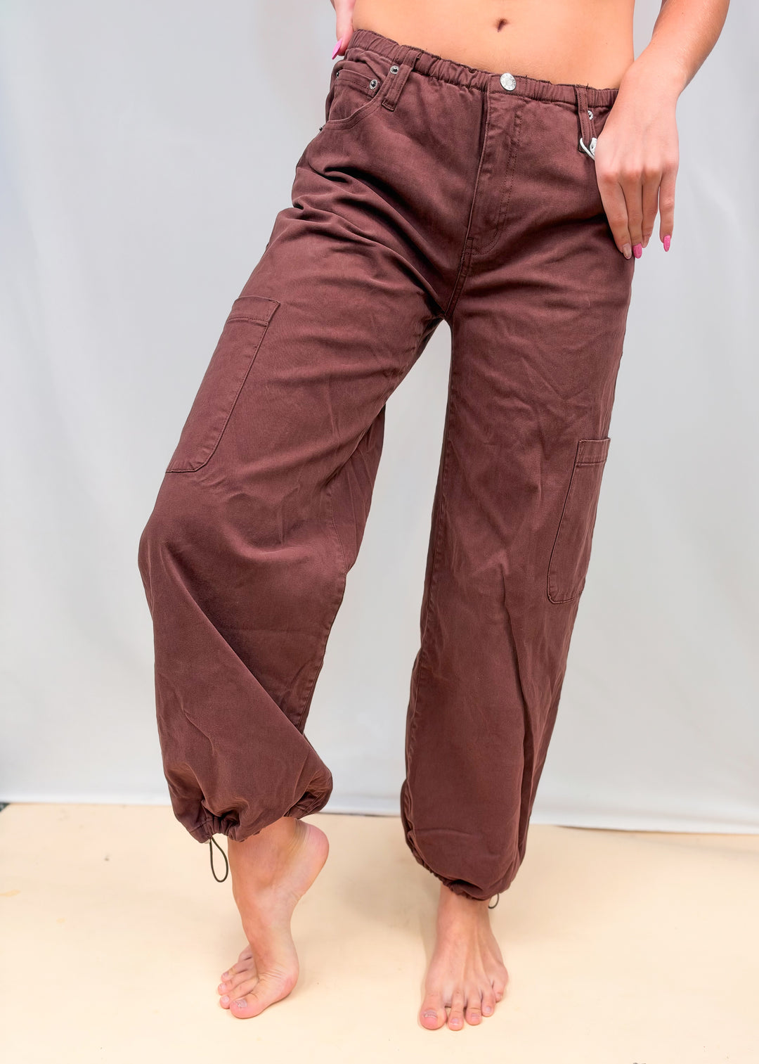 Woman wearing dark red/brown harem style pants on plain background