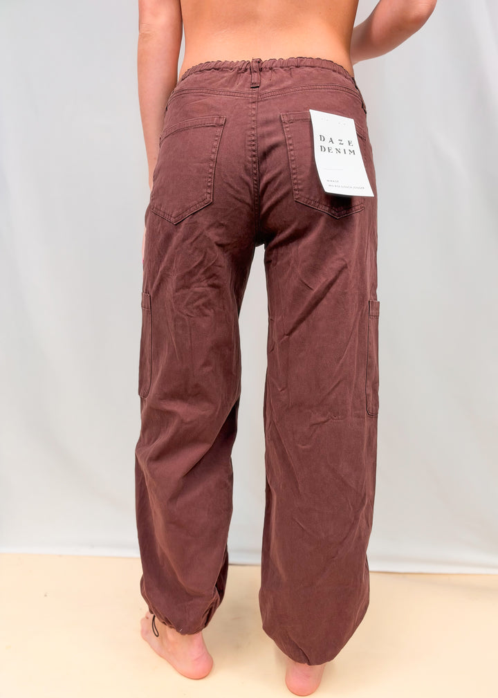 Woman shown from back view wearing dark red/brown harem style pants on plain background