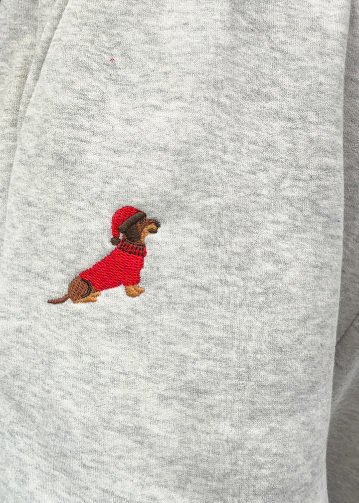 Close up of grey sweatpants with embroidered dog wearing red sweater and santa hat