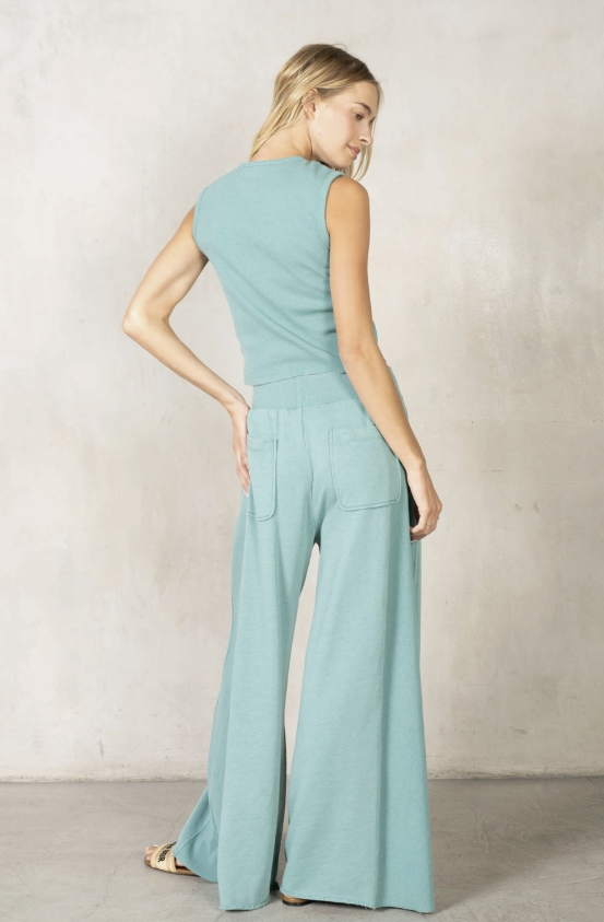 Woman wearing a light blue jumpsuit against a plain background