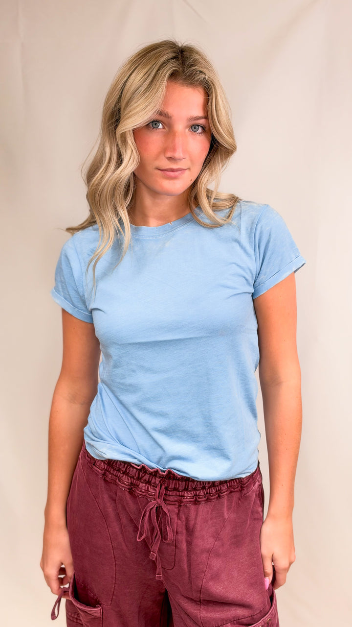 Woman wearing blue tee with maroon pants on plain background