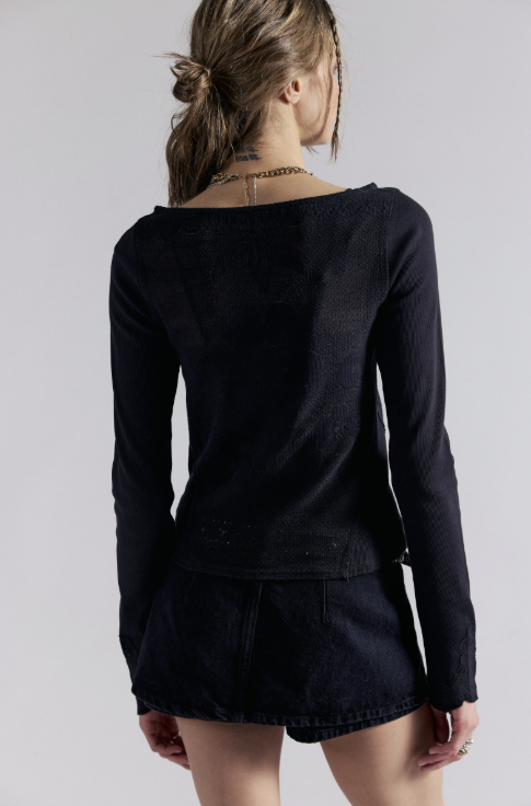 A woman shown from the back wearing a dark navy long-sleeve top and matching dark denim shorts against a light gray studio background.