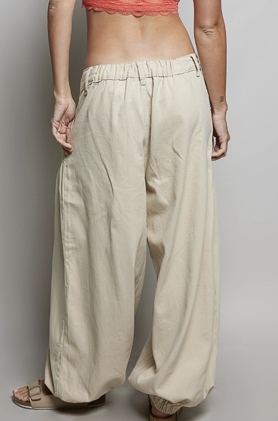 Woman wearing beige balloon pants on plain background