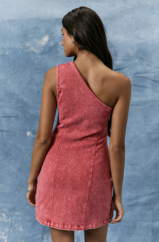 Woman wearing a red denim dress against a textured blue wall