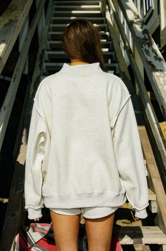 Person wearing a light gray sweatshirt and shorts on a wooden staircase