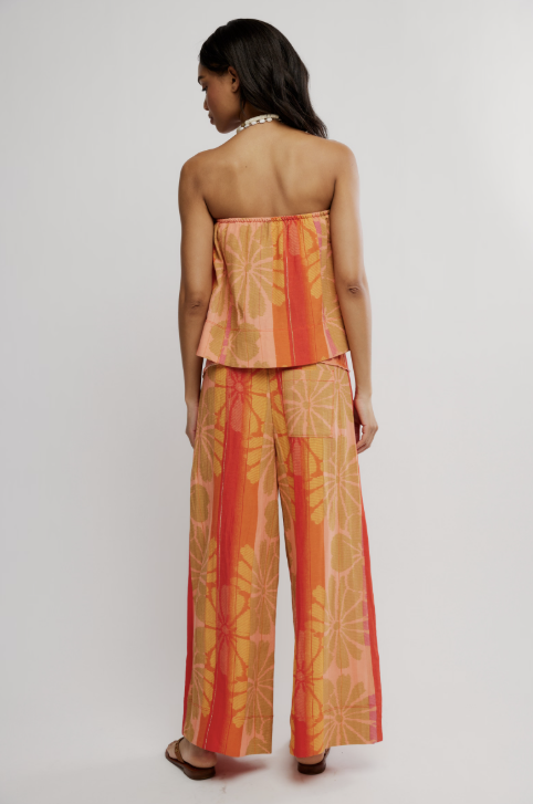 Woman wearing a strapless top and wide-leg pants with a floral pattern on a white background