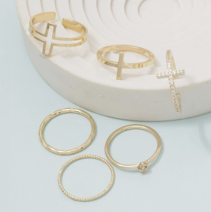 Multiple gold rings with crosses on jewelry dish 