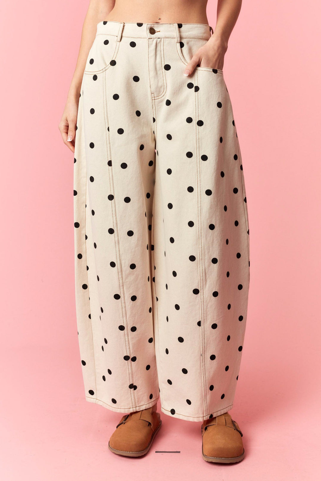 Person wearing polka dot pants on a pink background