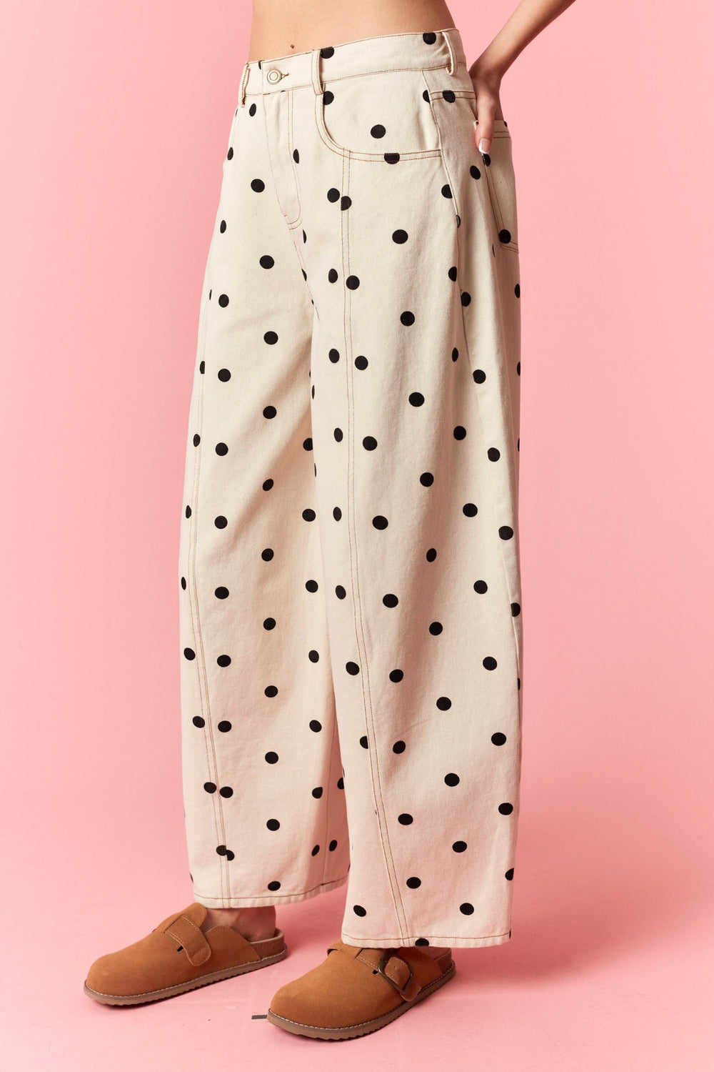 Polka dot jeans worn by a person on a pink background