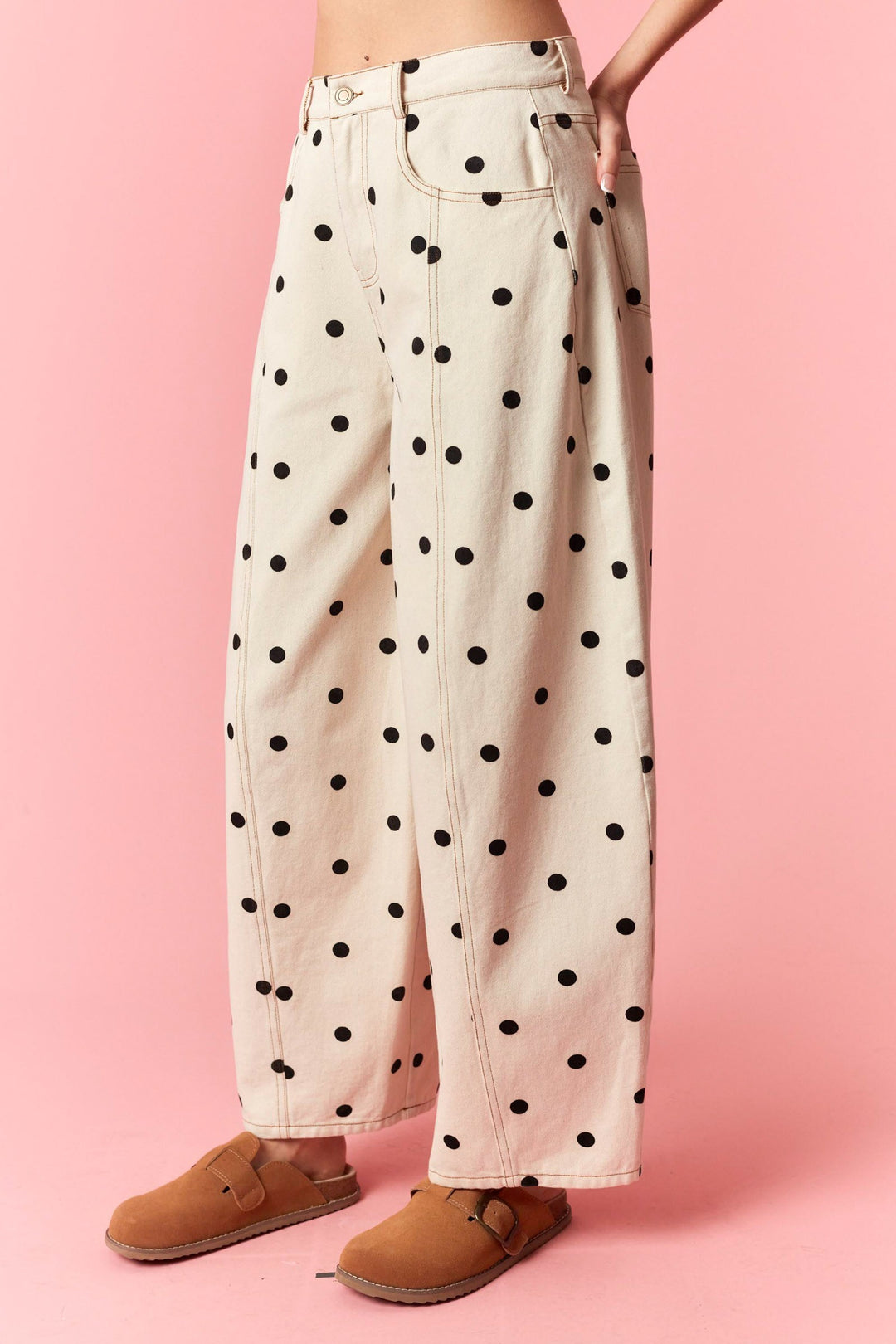 Polka dot jeans worn by a person on a pink background