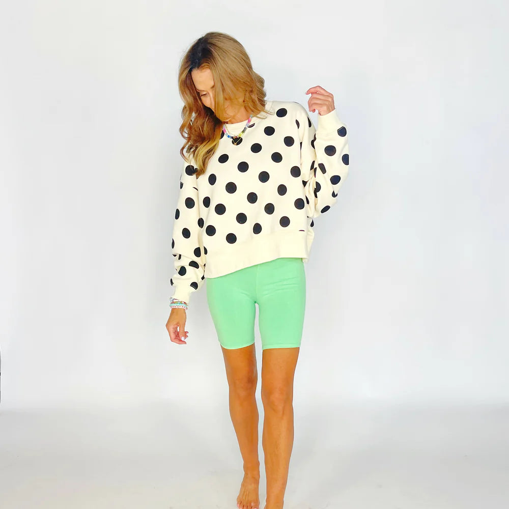 Woman wearing a polka dot sweater and green shorts on a white background