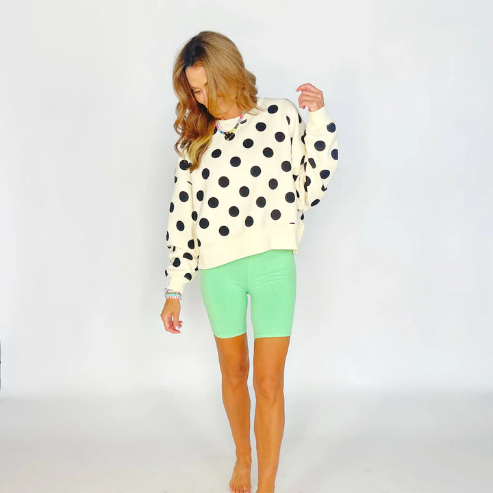 Woman wearing a polka dot sweater and green shorts on a white background