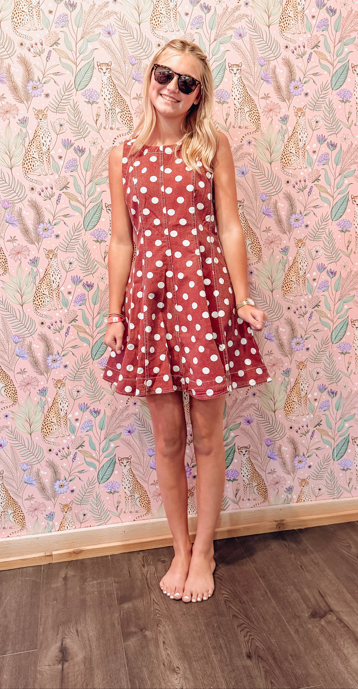 Woman wearing red polka dot dress in front of floral and animal print wall