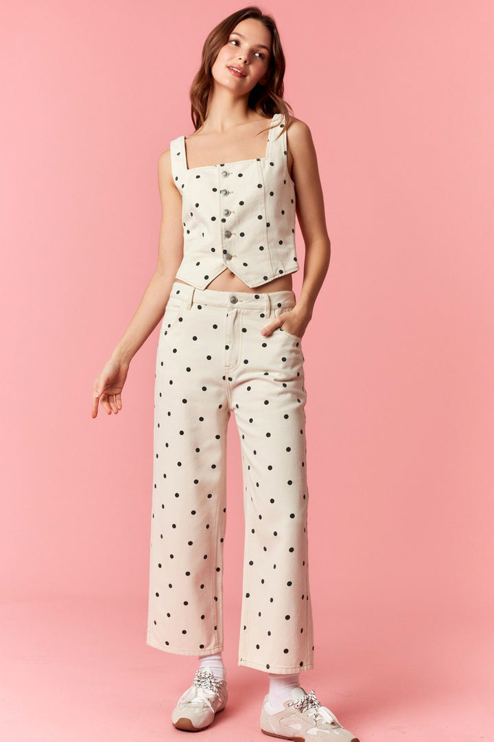 Woman wearing a polka dot top and pants on a pink background