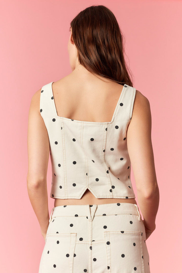 Woman wearing a polka dot top and skirt on a pink background