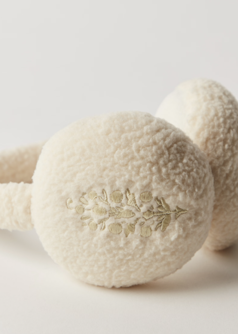 Pair of cream plush fleece ear warmers on plain background with logo